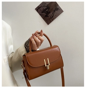 Detail of vintage caramel brown crossbody bag with gold H-shaped clasp and top handle