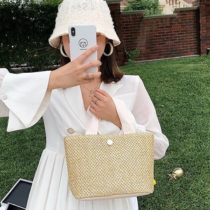 Handmade straw tote bag with white handle and button detail for summer beach vacations