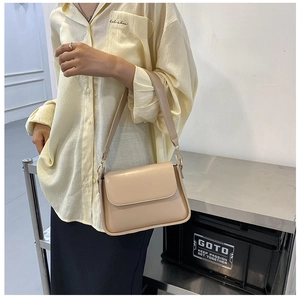 Minimalist beige baguette bag with flap cover and wide shoulder strap in a stylish scene