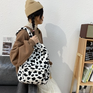 Fuzzy cow print plush backpack for women featuring a minimalist black and white design
