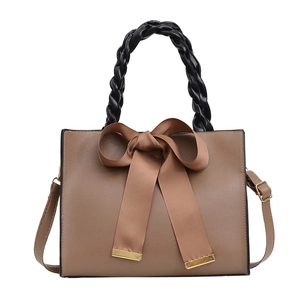 Sac à main marron pour femme avec grand nœud et poignée tissée noire sur fond blanc