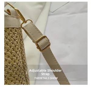 Detail of adjustable cream leather strap and gold buckle on woven straw bucket bag