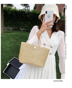 Detail of straw woven tote bag with white round buckle and pink fabric handles