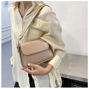Detail of a beige matte leather baguette bag with flap closure and adjustable strap
