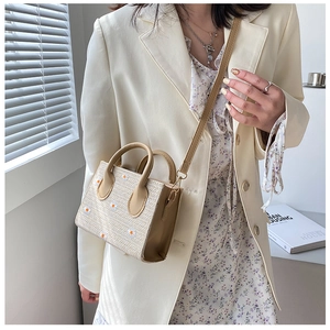 Détail du sac bandoulière beige tissé avec broderie marguerite et lanière en cuir souple