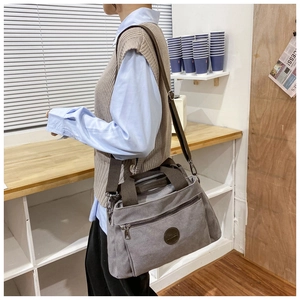 Detail of grey canvas travel bag with brown nylon strap and leather patch for men