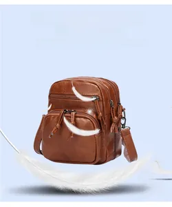 Detail view of a brown faux leather crossbody bag with multi-pocket design and adjustable strap