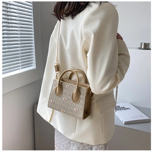 Détail d'un sac en paille avec broderie de marguerites et une fine bandoulière