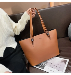 Gros plan détaillé d'un grand sac cabas en cuir marron avec de fines anses et logo