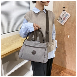 Detail view of a vintage grey canvas travel bag with brown straps and leather logo patch