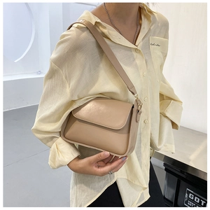 Detail view of khaki baguette bag worn over the shoulder with striped shirt