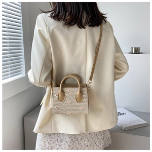 Détail du sac en paille avec marguerites brodées présenté dans un cadre chic