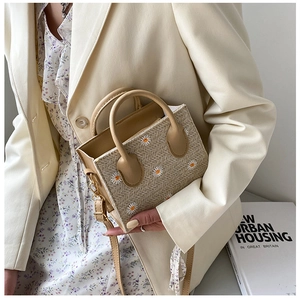 Vue détaillée du sac cabas en paille beige avec broderie de marguerites et anses