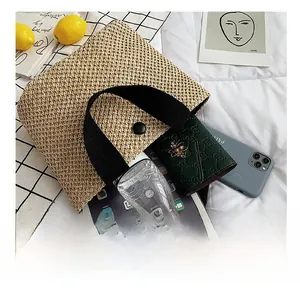 Detail view of woven straw tote bag with black handles showing spacious interior capacity