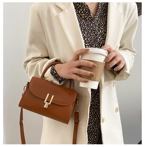 Detailed shot of caramel brown leather handbag with gold clasp and adjustable shoulder strap