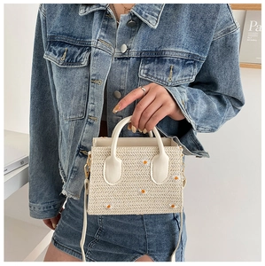 Détail du petit sac cabas en paille crème avec broderie marguerite porté par le mannequin