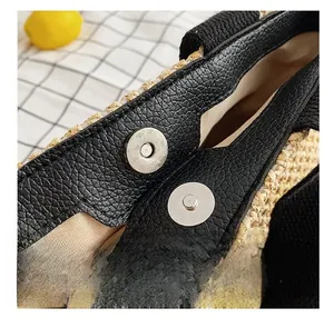 Close-up of silver magnetic clasp on straw woven bag with black leather trim details