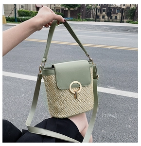 Detail of hand-held straw bucket bag with green leather flap and golden ring closure