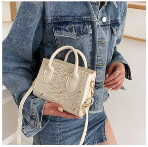 Détail de la broderie marguerite sur un sac cabas en paille écru porté par un mannequin