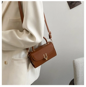 Brown leather retro square bag with gold H-buckle worn over a white blazer