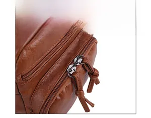 Detailed close-up of brown litchi pattern leather bag with smooth dual metal zippers