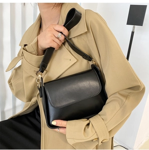 Minimalist black leather baguette bag styled with a beige trench coat for a chic look