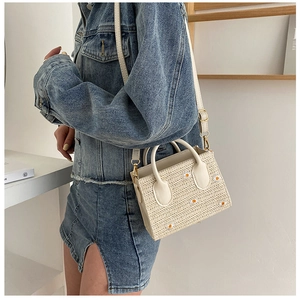 Sac bandoulière en paille brodé de marguerites porté par un mannequin en jean