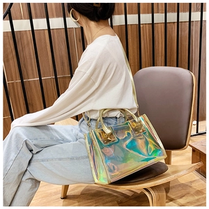 Holographic clear handbag with gold metal handles shown on model in casual style