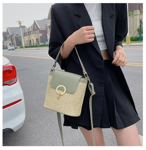 Detail of straw crossbody bag with green leather flap and golden ring metal clasp