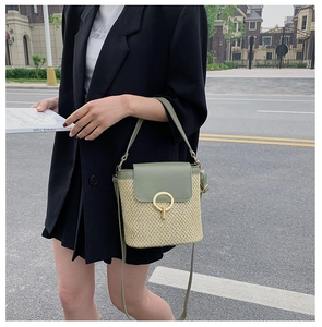 Detail view of bean green PU leather and woven straw bucket bag with gold ring closure