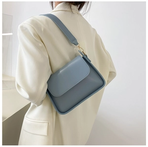 Light blue matte leather baguette bag worn on shoulder with minimal gold metal details