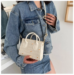 Détail du sac cabas en paille crème avec broderie marguerite et détails dorés