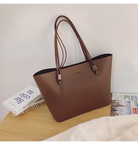 Détail d'un sac cabas en cuir marron avec texte FASHION et boucles en métal argenté