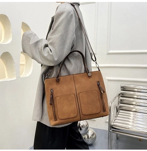 Close-up of brown matte suede tote bag featuring front dual zipper pockets and top handles