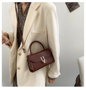 Detail view of smooth dark brown leather bag with a stylish golden geometric buckle