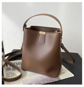 Nahaufnahme der karamellfarbenen Eimer-Tasche aus Leder mit goldener Hardware-Details