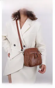 Detailed view of brown vintage messenger bag with multiple zip pockets and soft leather texture
