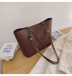 Détail du sac cabas en cuir marron foncé avec texte FASHION sur fond de bois moderne