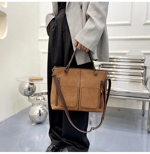 Detail view of warm brown faux suede tote bag featuring front pockets and metal zippers