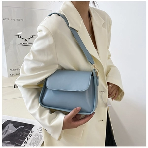 Light blue minimalist bag paired with a white blazer for a stylish commuter look