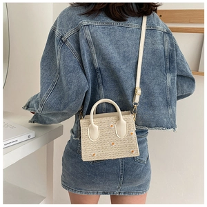 Détail du sac en paille avec broderie marguerite et poignées blanches supérieures