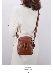 Detail of vintage brown leather crossbody bag featuring multi-pocket design and tassels