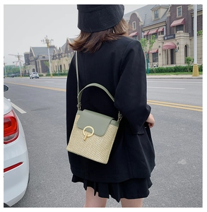 Detailed shot of straw woven crossbody bag with green leather flap and golden metal lock
