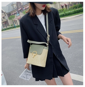 Close-up of straw bucket bag with green leather flap and golden round metal clasp