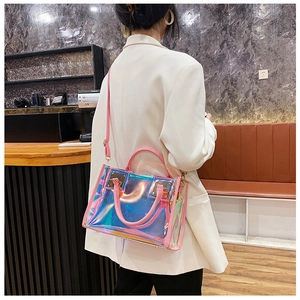 Detail of pink leather handles and gold metal buckles on a holographic PVC tote bag