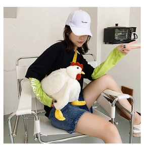 Detail of cute white plush chicken crossbody bag with red comb and yellow strap
