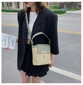 Detail of straw bucket bag featuring sage green leather trim and golden ring closure