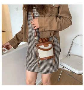 Detail of bucket bag showing canvas and caramel leather textures with drawstring closure