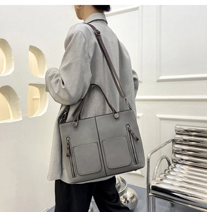 Grey matte leather tote bag shown on model featuring double pockets and crossbody strap