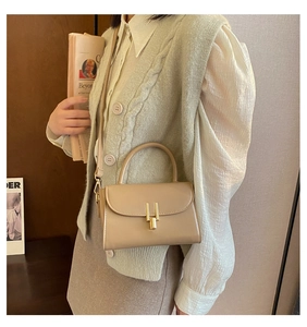 Detail view of beige retro crossbody bag featuring a distinctive golden H-shaped hardware lock